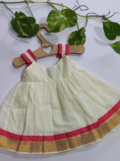 This Kasavu dress is perfect for Onam or Vishu. I've added a touch of pink handloom detailing to the traditional off-white and gold, making it unique and pretty for your little one.