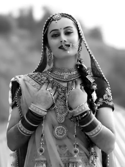 A beautiful three-quarter length bridal portrait in black and white, emphasizing her pose and the texture of her attire.