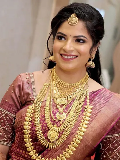 The smile of a happy bride says it all. She looks absolutely stunning in her mauve Kanjivaram saree and layers of traditional gold necklaces.