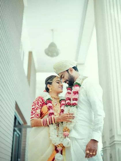 A classic, romantic portrait of a couple in their wedding attire, framed by the grand white pillars of their venue.