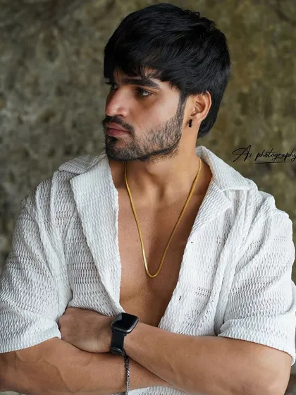 A strong portrait with crossed arms, highlighting bicep and chest definition. This confident pose in a stylish, open shirt is great for a fitness influencer's portfolio.