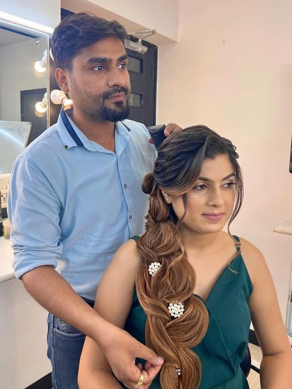 An instructor provides one-on-one guidance to a student, helping them perfect an intricate braided hairstyle on a live model.