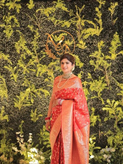 A full-length shot of the bride against a green wall. Her makeup is light and timeless, allowing her regal silk drape to take center stage.