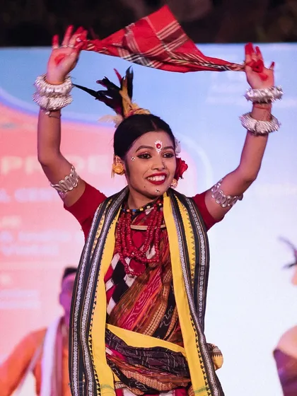 A performer holds up a red scarf, smiling brightly at the audience. This is a perfect example of the joyful, celebratory moments I aim to capture at cultural festivals.