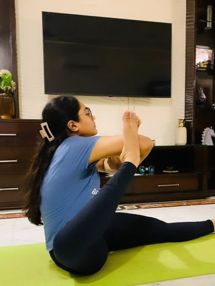 This student is working on a seated hip-opening pose, showing focus and determination on her yoga journey.