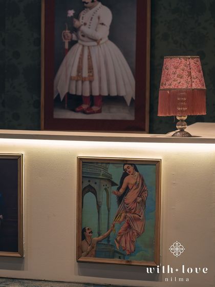 A detail of the bar, where a vintage-style lamp sits beside Raja Ravi Varma paintings. Every element is chosen to enhance the artistic, historical theme.