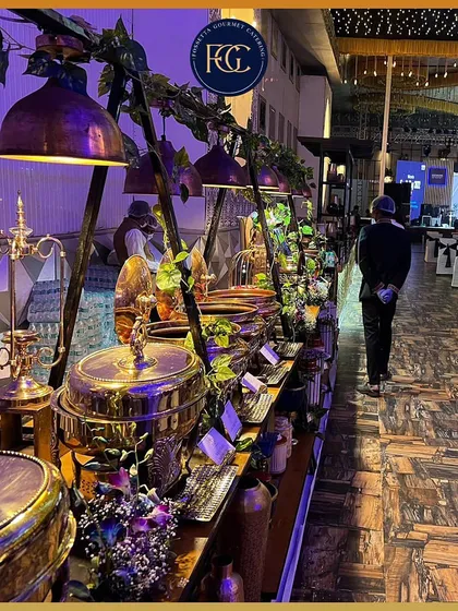 A sprawling buffet line at a large corporate event. The dramatic purple lighting and extensive food selection demonstrate our capability to handle large-scale, high-end functions with style.