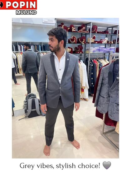 A client trying on a grey suit jacket with a black lapel in my store. Grey is a versatile color that works for both day and evening events.