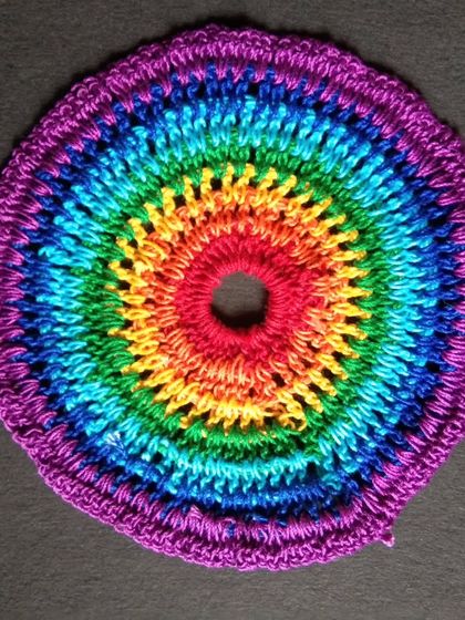 A 6-inch rainbow crochet doily. This can be used as a coaster, a base for a small vase, or as part of a dreamcatcher.