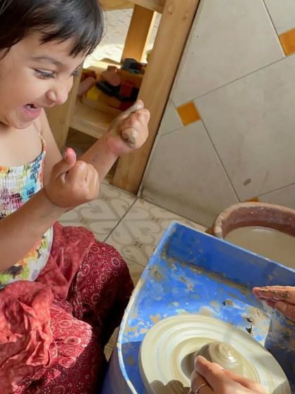 The excitement is real. This little girl is thrilled as she gets her hands messy and shapes the clay, discovering a new way to express her creativity.