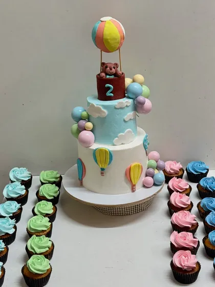 The hot air balloon cake paired with matching pastel-coloured cupcakes, creating a beautiful and cohesive dessert table.