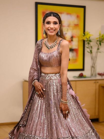This bride's sangeet look is all about modern glamour. The shimmering pink lehenga is paired with a sleek hairstyle and radiant makeup that catches the light beautifully.