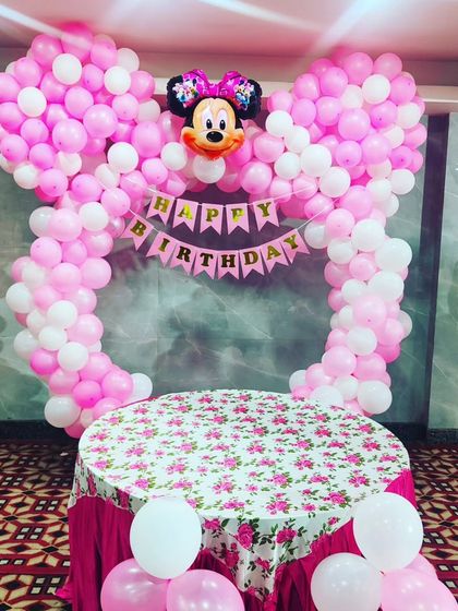 For a child's birthday, I can create themed decorations like this Minnie Mouse setup. It includes a large balloon arch shaped like mouse ears and a matching table cover for the cake cutting ceremony.
