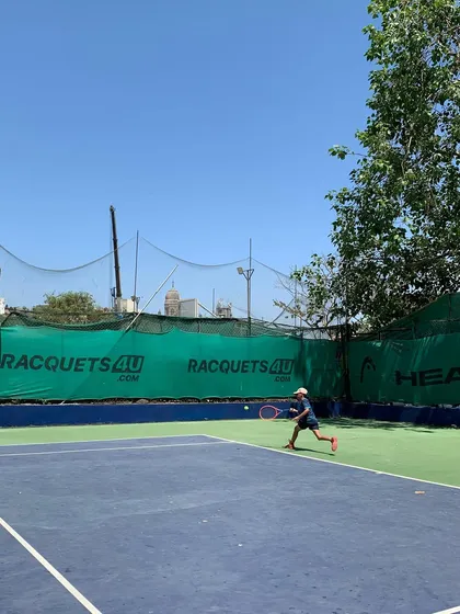 A young player in action during the TenniStation Season 12 tournament, focused on returning a shot.