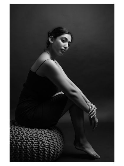 A seated black and white portrait that plays with shadows and form. The composition is simple yet powerful, focusing on the model's elegant posture.