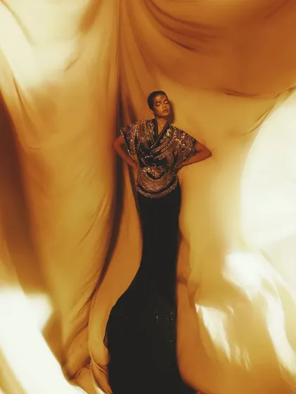 A dramatic, flowing shot from the "Dynasty of Gold" series. The makeup features shimmering gold tones and a regal feel.