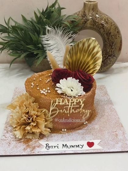 A golden glittery cake with hues of red for a "Pyari Mummy." This design is all about glamour, featuring a full glitter finish, feathers, and florals.