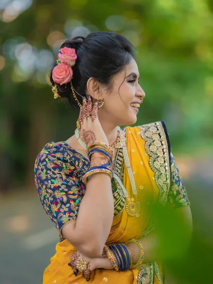 A side profile showcasing the messy khopa hairstyle adorned with fresh flowers, a modern twist on a traditional bun.