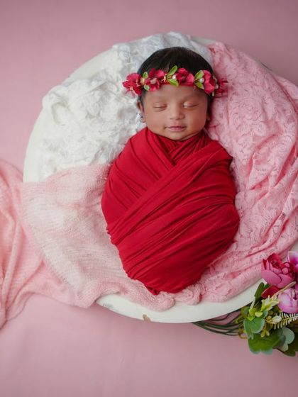 A vision in red. This simple setup with a swaddled baby and a few flowers is elegant and timeless.