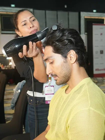 Our artists are trained to work with both male and female models. Here, a student styles a male model's hair backstage at a major fashion week.