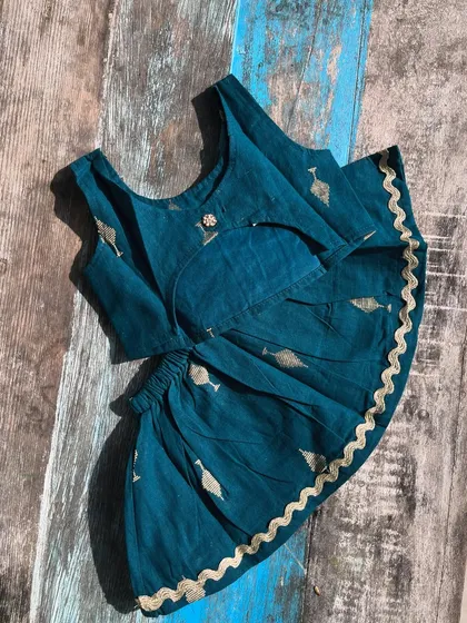 A different view of our rich teal handloom cotton dress, showcasing the pleated skirt and gold scalloped edges perfect for twirling.