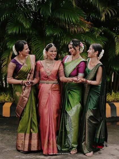 The bride with her bridesmaids, all dressed in beautiful silk sarees, sharing a happy moment together.
