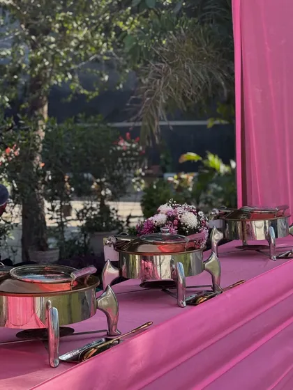 A vibrant pink-themed setup for a daytime wedding function. Our buffet counters can be customized to match your event's color palette and decor.