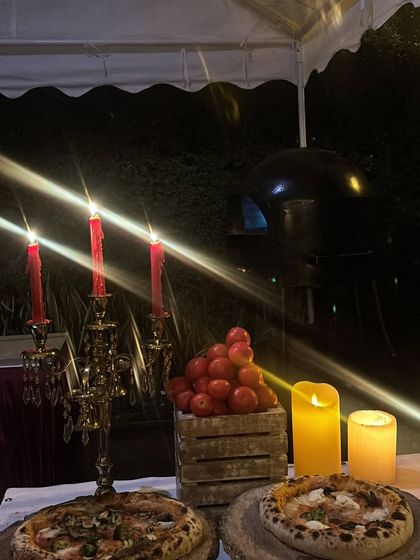 For a more dramatic evening look, I can decorate the station with elegant candelabras and candles. This setup, from a special birthday party, shows the wood-fired oven glowing in the background.