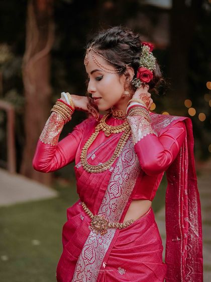 A beautiful shot of the bride adjusting her hair, adorned with flowers, showcasing the intricate details of her bridal look.