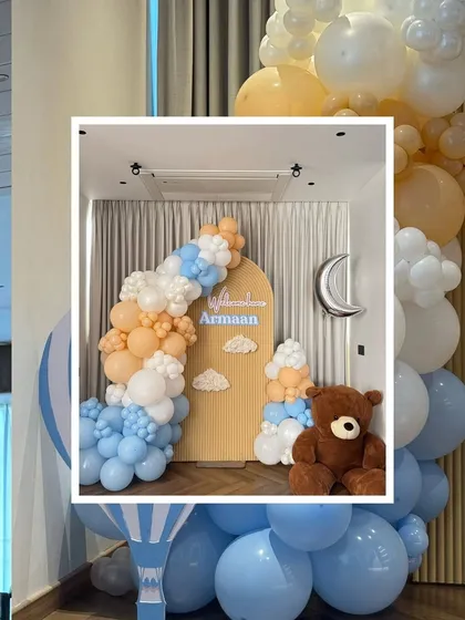 A wider view of the "Welcome Armaan" decor, showing how the central photo backdrop is enhanced by a large hot-air balloon sculpture made of balloons, adding a whimsical touch to the welcome home celebration.