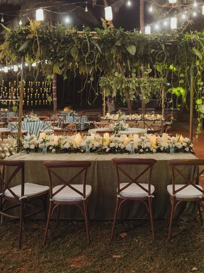 The beautifully styled head table, with a canopy of natural greenery overhead and a line of candles creating a warm and intimate focal point.