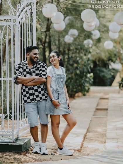 A casual and happy shot of a couple in a garden, with hanging paper lanterns adding to the charming atmosphere.