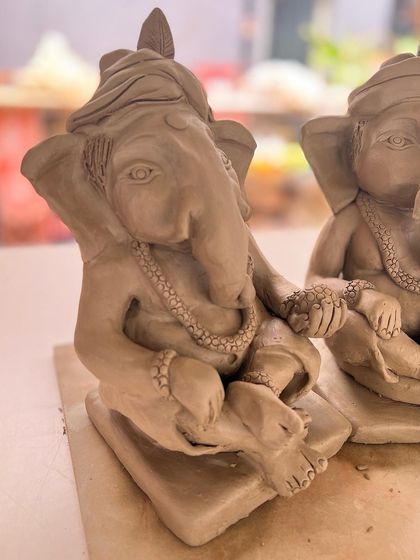 A pair of Ganesha idols in progress, showing the beautiful details of the clothing and posture.