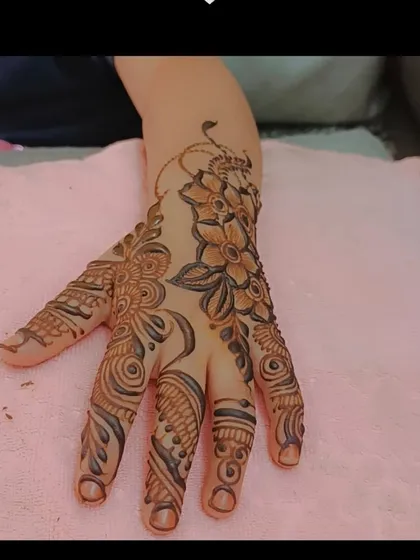 A clear, top-down view of the fresh floral henna design on a pink background. You can see the combination of flowers, leaves, and swirls that make up this popular pattern for kids.