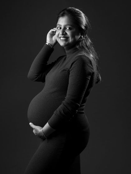A classic black and white maternity portrait. The mom-to-be's gentle smile and the soft lighting create a timeless and elegant photo that she will cherish forever.