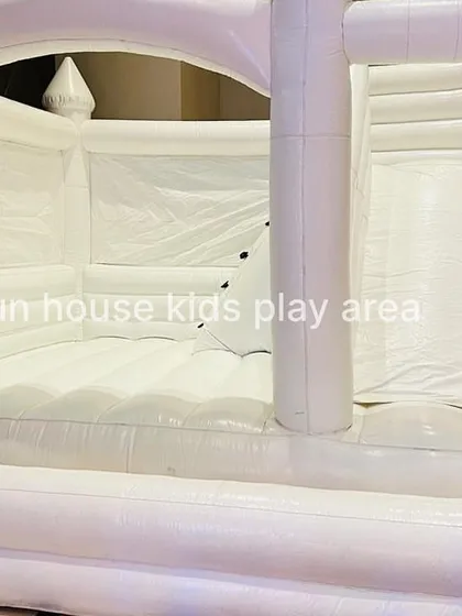 A detailed shot inside the white bounce castle, showing the climbing ramp with safety holds and the entrance to the slide.