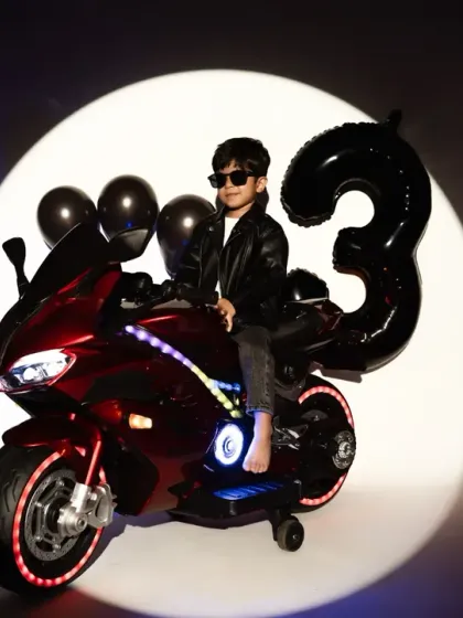 Celebrating a third birthday with style. This fun, biker-themed studio shoot features dramatic lighting and cool props like a toy motorcycle, perfect for capturing your child's personality.
