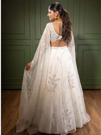 A view of the back of the white embroidered lehenga, showing the beautiful sleeve details and the delicate tie-up back. Every angle is designed to be picture-perfect.