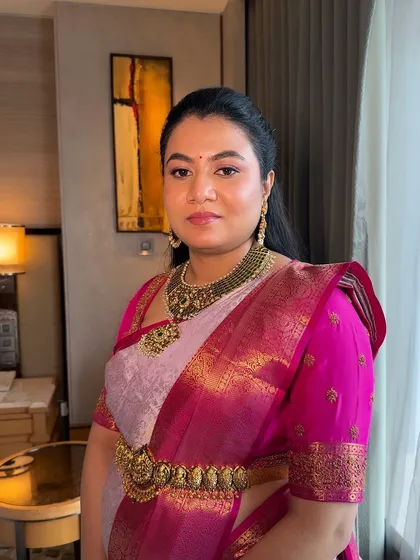 This full-length view shows how the makeup harmonizes with the entire outfit, including the beautiful pink silk saree and traditional gold jewelry.
