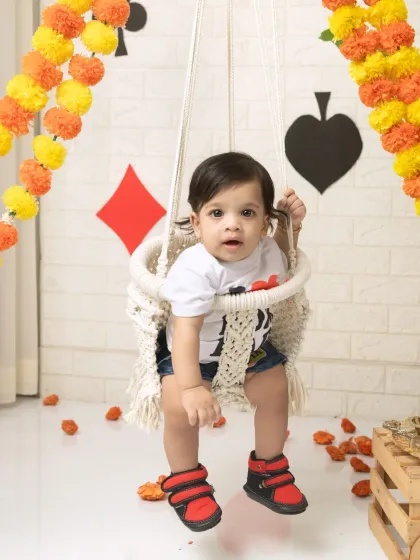 A full-length shot of a baby boy on the Raja swing, with the festive decorations creating a lively background.