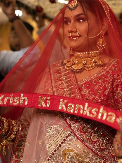 A close-up of the bride's expression. Her makeup looks flawless and speaks volumes, even through the sheer red veil.