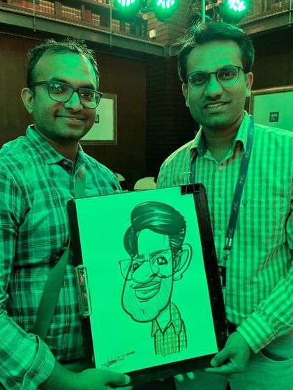 Two doctors posing with a caricature at the Sancheti Hospital event. The green lighting added a cool effect to the photo.
