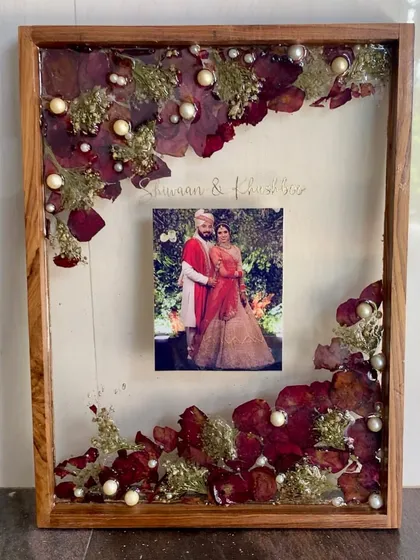 A finished varmala preservation frame in a wooden shadow box. This is a timeless way to display your wedding flowers and photo.