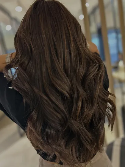 The back view shows how the mocha brown and beige highlights are seamlessly blended. The long layers add beautiful texture and volume.