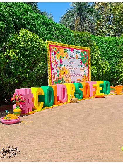 A large, 3D "#COLORSOFEO" sign served as the primary branding and photo-op for this corporate Holi event. The colorful letters and floral details created a fun, shareable moment.