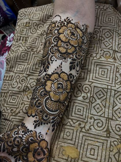 A close-up of the forearm, showing the intricate details of the floral pattern. Each petal and leaf is carefully drawn.