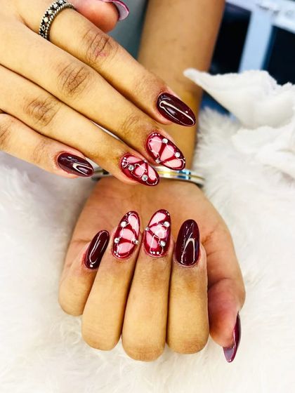 A striking design featuring butterfly wings in a deep maroon shade. The wings are accented with tiny pink rhinestones for a touch of sparkle.
