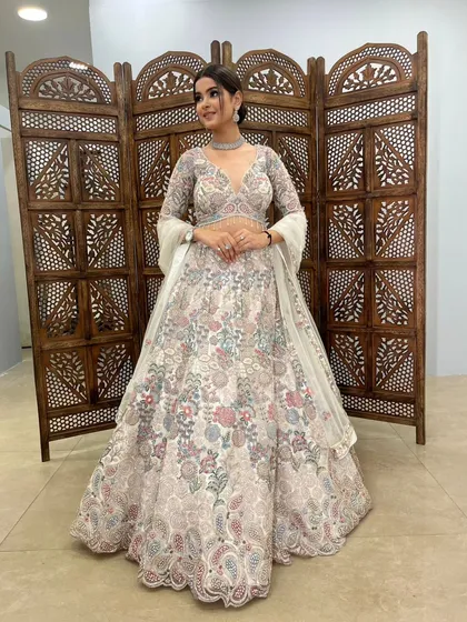 A full, smiling shot of a client looking beautiful in this floral embroidered lehenga.