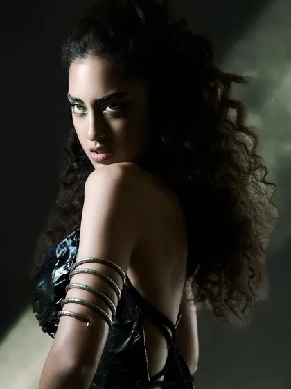 In this shot, the 'ray of light' technique is used to highlight the model's profile and the unique snake-like arm cuff. The dramatic shadows and intense gaze create a powerful and serpentine mood, fitting for an edgy accessory story.