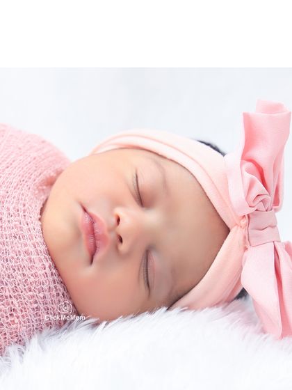The perfect pout of a sleeping baby girl. This detailed shot highlights her rosy cheeks and the sweet pink bow on her head.
